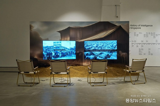 호 루이 안, '역사의 형상들과 지능의 토대(Figures of History and the Grounds of Intelligence)' 2024, 실시간 AI 생성 이미지와 비디오 설치, 컬러, 사운드, 시트지 가벽, 모래, 캠핑 의자, 75분.