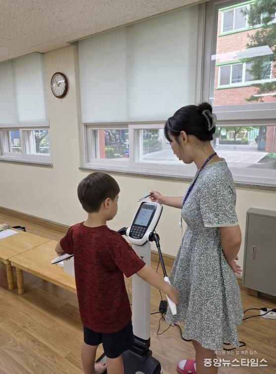 아동이 사전 신체 계측을 하고 있다.